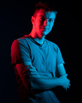 Handsome guy posing in studio on black background. Isolated with blue and red color gel