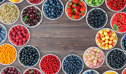 A set of berries in the round plates. Brown wooden background. Copy space. Flat top view.