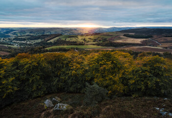 Stanage Edge, Peak District UK. An autumn sunset casting string light on the hills in the back ground. 