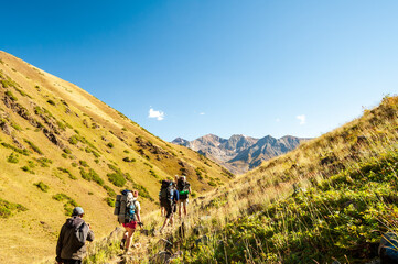 Obraz premium Group of young hikers trekking in mountains. Two women two men backpacking in summer near Sary Chelek lake, Sary-Chelek Jalal Abad region, Kyrgyzstan, Trekking in Central Asia.