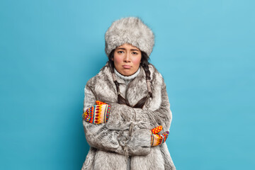 Unhappy scandinavian woman in fur hat and coat crosses hands and feels freezing trembles during...