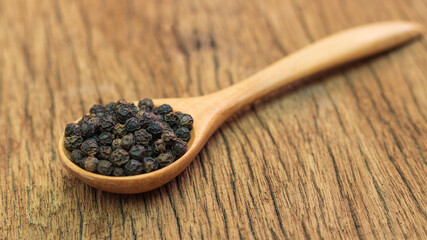 Close Up of peppercorn in wooden spoon on old wooden table.