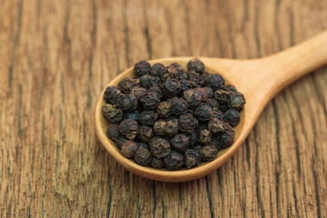 Close Up of peppercorn in wooden spoon on old wooden table.