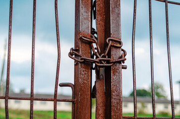 Old metal gate closed with a rusty chain