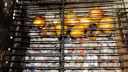 Grilled patatoes on the hot flaming charcoal grill