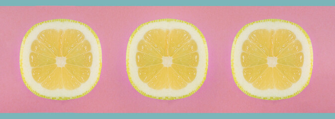 Obraz premium Lemon opened by the pulp on a pink background. Citrus slices cut on a pink and blue banner.