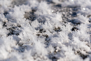 Snowy white background with frosty crystals and curly snowflakes close-up. Winter is a cold season with a blinding white bright color