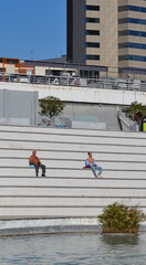 Barcelona, Spain, October 24, 2020: Two man with no t-shirt suntanning on symmetrical stairs in a park in Barcelona