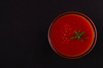 Glass of tomato juice on a black background. Flat lay.
Copy space.