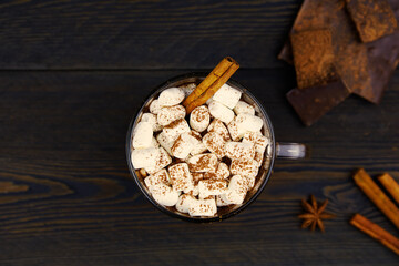Obraz na płótnie Canvas Homemade hot chocolate with cinnamon and marshmallow in a cup on a wooden background. Top view.
