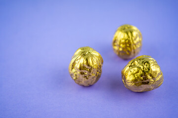 Three walnuts colored in golden color on a violet background. Selective focus 