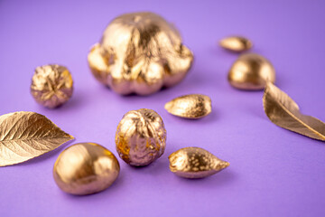 Pumpkins, nuts and leaves painted in gold on a purple background. Flat layout with space for text. Selective focus background