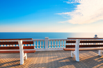 Fototapeta na wymiar Two benches on the terrace with sea view at sunset. Beautiful summer seascape, travel destination concept.