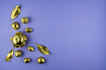 Pumpkins, nuts and leaves painted in gold on a purple background. Flat layout with space for text. High quality photo