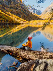 Happy woman at crystal lake in the autumnal mountains. Mountain lake and traveller girl