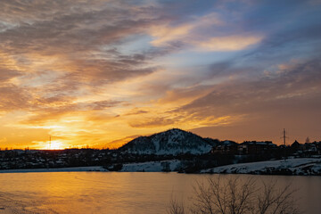 The colorful sky at sunset on a clear day plays with several colors , contrasting and rich beautiful view of the glow near the mountain and the city in winter