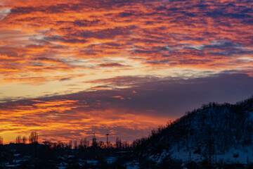 The colorful sky at sunset on a clear day plays with several colors , contrasting and rich beautiful view of the glow near the mountain and the city in winter