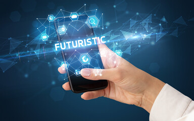 Female hand holding smartphone with FUTURISTIC inscription, modern technology concept