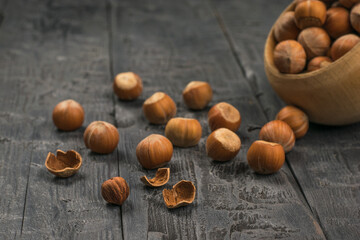 Whole and split hazelnuts are spilled on a wooden table.