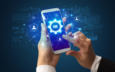 Female hand holding smartphone with HR abbreviation, modern technology concept