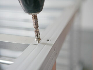Close up of an electric screwdriver tightening a screw to assemble an aluminum storage shelves
