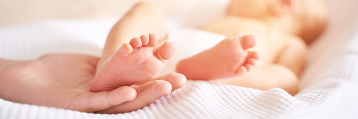 Newborn tiny legs. Sister holding little feet. Two people. Healthcare concept. Unrecognised modern...