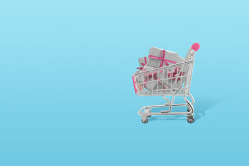 Concept of buying Christmas gifts. Shopping cart full of presents. Minimal concept with pastel colors