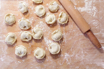 Closeup on semi-finished pelmeni dumplings on the wooden board.