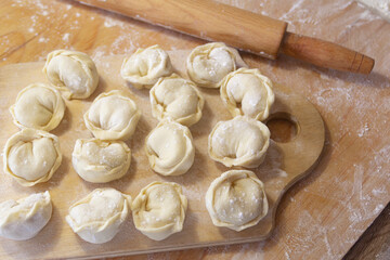 Closeup on semi-finished pelmeni dumplings on the wooden board.