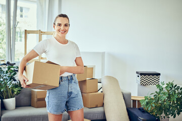 Portrait of woman moving to new home standing with cardboard box smiling.