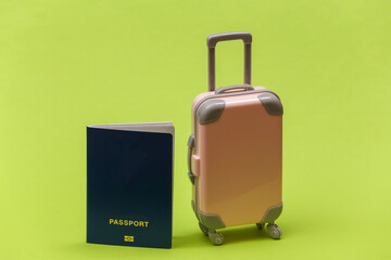 Travel or trip concept. Mini plastic travel suitcase with passport on green background. Minimal style