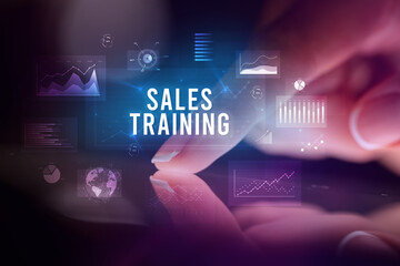 Finger touching tablet with charts and SALES TRAINING inscription, business concept