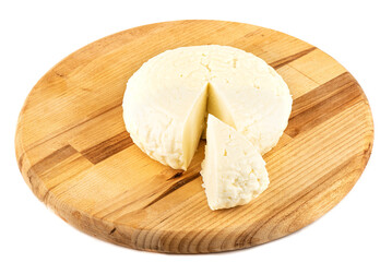 Round soft cheese with a cut triangular piece on a wooden cutting board.