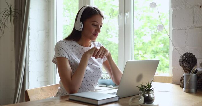 Smiling young european appearance woman in headphones finishing video call conversation in computer application, making farewell bye-bye gesture, e-learning distant education, remote working meeting.