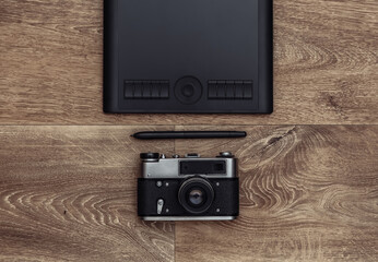 Graphic tablet with pen and camera on wooden background. Top view