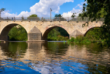 Fototapeta premium Beautiful old bridge over a calm river on a Sunny day