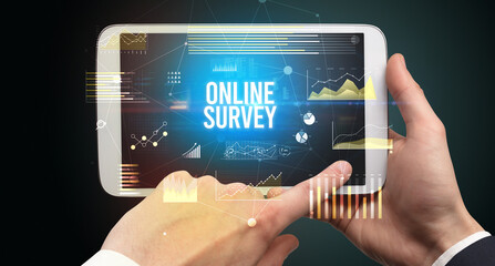 Close-up of hands holding tablet with ONLINE SURVEY inscription, modern business concept