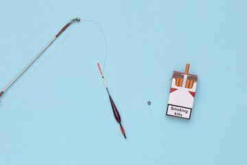 Smoking addiction. Pack of cigarettes on the hook of fishing rod
