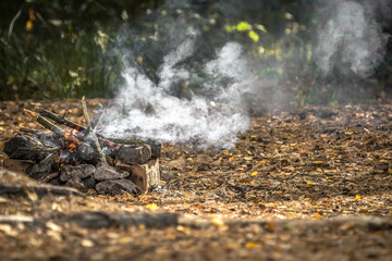 White smoke from the fire. Picnic in the autumn forest. Kindle Fire. Boy scout camp. Burning...