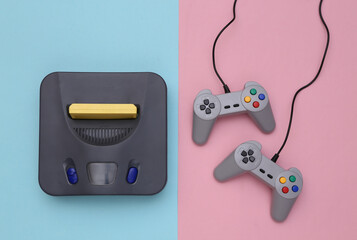 Retro video game console with joysticks on pink blue background. Top view © splitov27