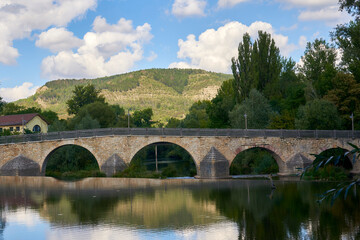 Beautiful old bridge over a calm river on a Sunny day