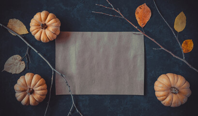Halloween grunge dark blue holiday background, pumpkins, dry branches and orange leaves decorations. Autumn composition frame, party invitation card, flat lay, vintage paper, copy space.