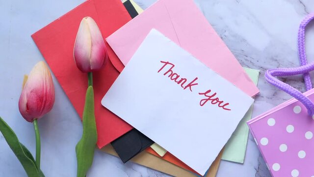 thank you message on paper with tulip flower on tiles background 