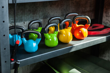 Kettlebells and sports equipment on a rack in a gym