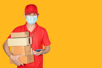 Fototapeta na wymiar Delivery man employee cap and shirt red uniform face mask holder parcel Box Mail box isolated on yellow background Service New normal after pandemic coronavirus concept