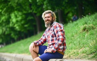 Naklejka na ściany i meble Bearded hipster relax outdoors. Man tourist sit riverside. Man with beard and moustache relaxing nature background. Tourism concept. Summer vacation. Nice day. Rest and relax. Relaxation and pleasure