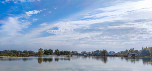 Sunny day on the perfect lake. Autumn lake with reflection on the water. Cloudy sky in the sunny day.
