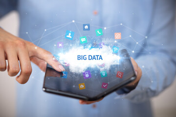 Businessman holding a foldable smartphone with BIG DATA inscription, technology concept