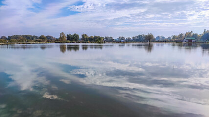 Sunny day on the perfect lake. Autumn lake with reflection on the water. Cloudy sky in the sunny day.