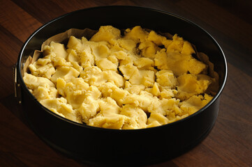 Raw dough broken into pieces in a cake mold. The process of preparation for baking the cake. Close-up, selective focus